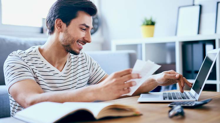 Photo of man with bills and laptop computer